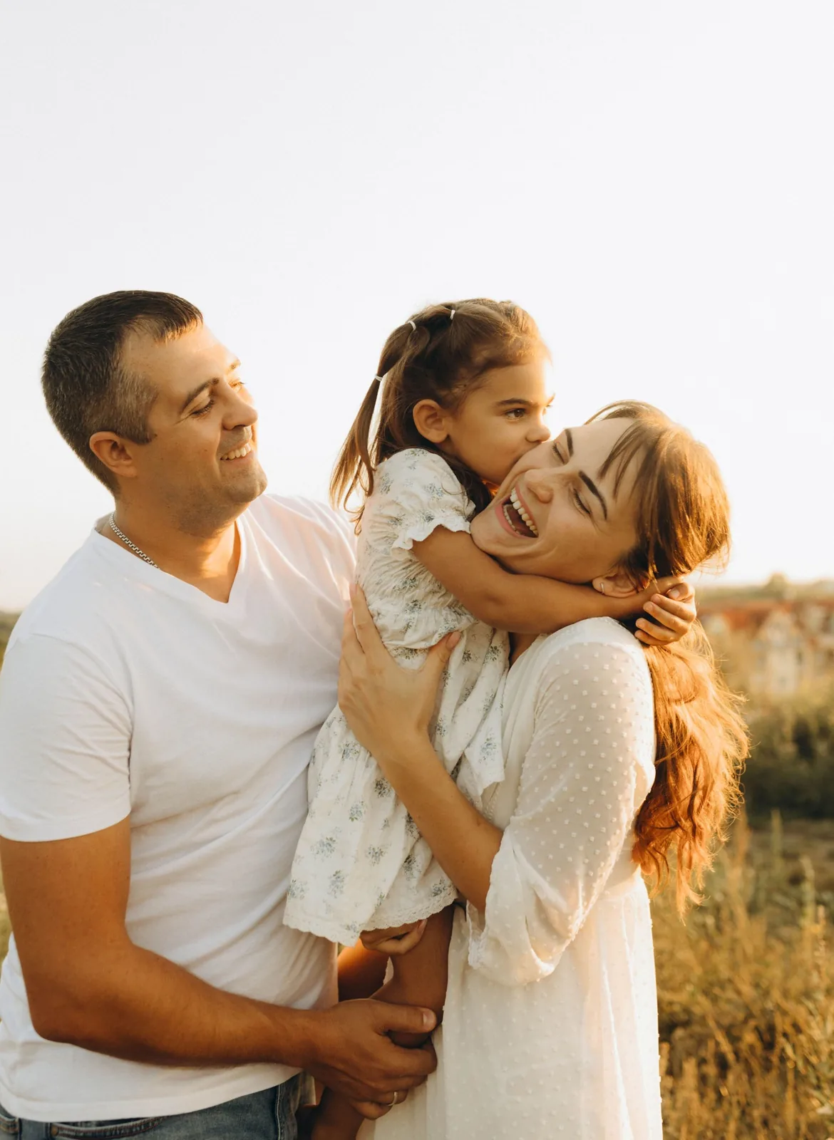 Padres abrazando a su hija en un entorno cálido y natural
