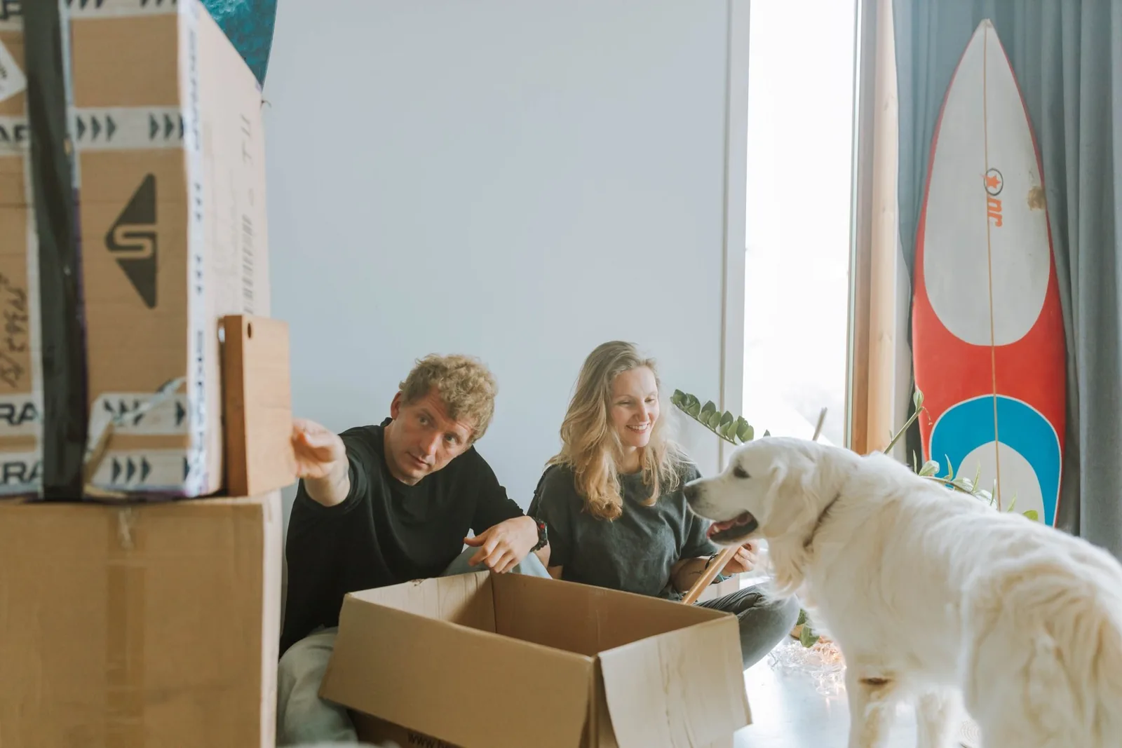 Pareja organizando cajas en una nueva vivienda junto a su perro
