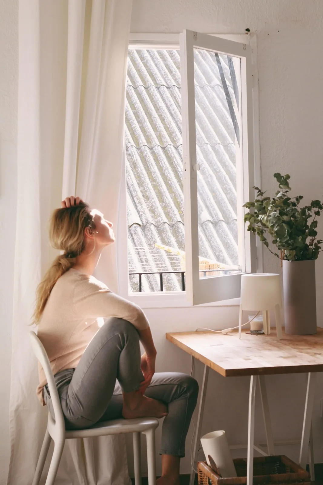 Mujer sentada junto a una ventana en una vivienda luminosa y tranquila