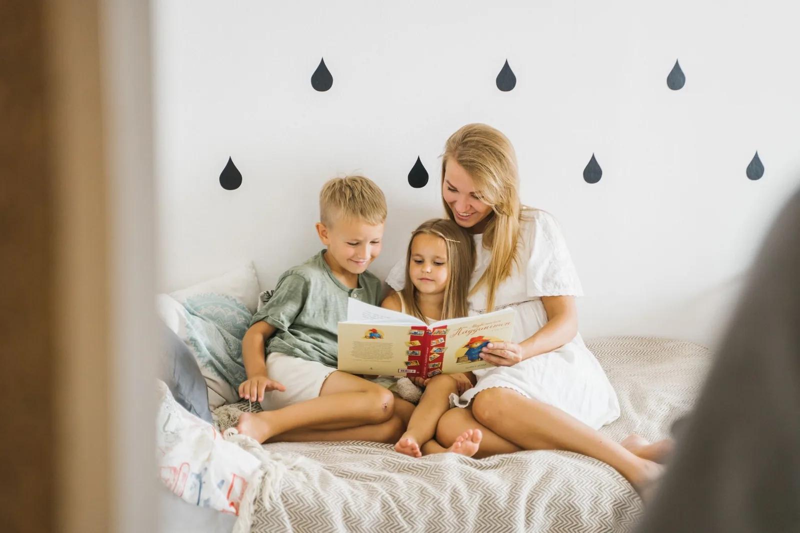 Madre rubia leyendo con sus hijos en una habitación luminosa