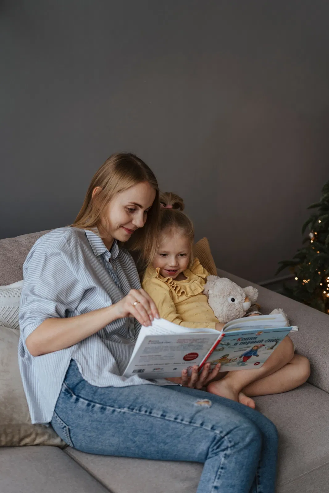 Madre leyendo con su hija en el sofá en un ambiente tranquilo